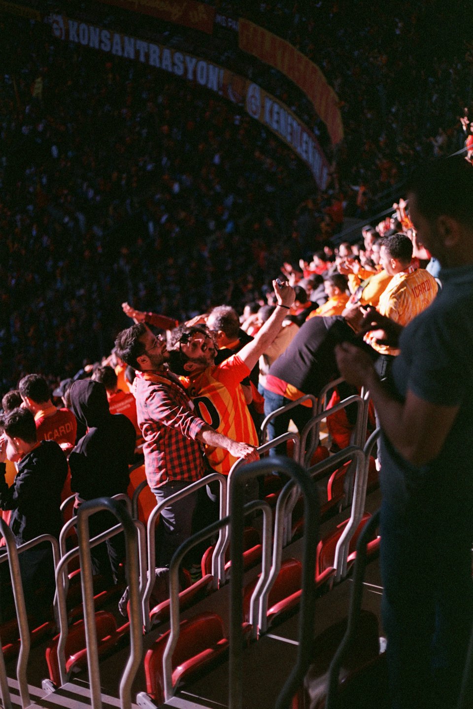 Tifosi sportivi esultano durante una partita in uno stadio affollato.